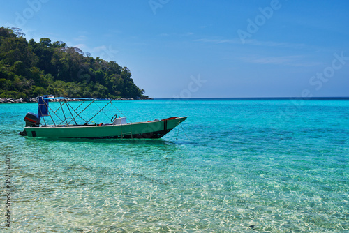 Beautiful nature landscape. White sandy beach and a boat in the turquoise sea. Paradise island. Perfect getaway. Travel concept and idea.