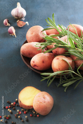 Raw red potatoes with fresh rosemary and garlic on blue background. Organic food