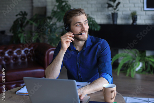 Confident man wearing headset speaking and watching business webinar training, listening to lecture.