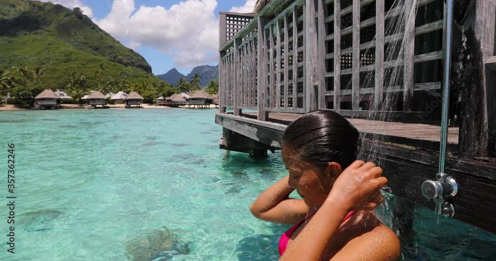 Travel luxury. Woman taking shower outside in bikini at resort hotel on