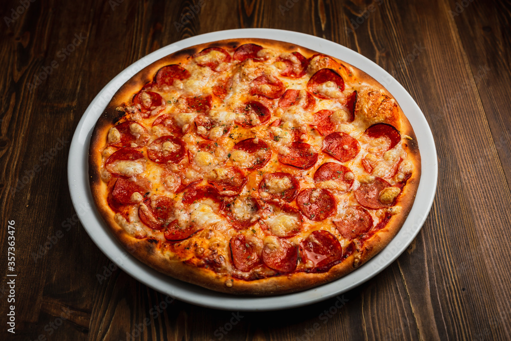 Pepperoni pizza with a nice crust, wooden background, low key