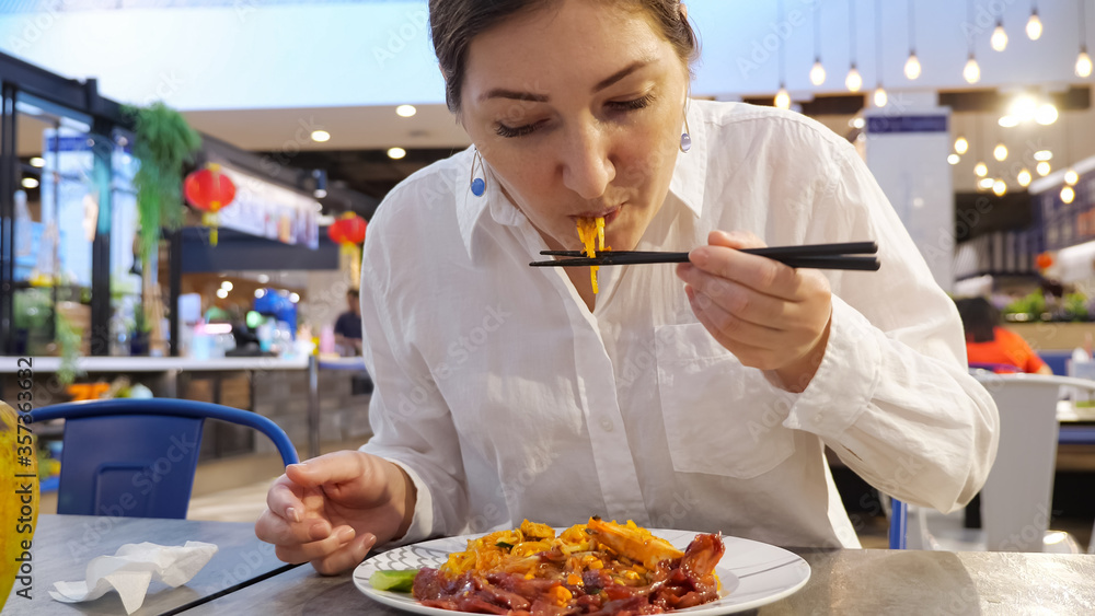 Young woman eating thai noodles with chopsticks. Young woman eating thai noodles with chopsticks.