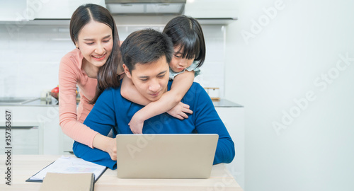 Happy young asian girl with her lovely parents using laptop computer for education and spent quality time together. Asian family. Social Distancing. Homeschooling. Work from home or love concept