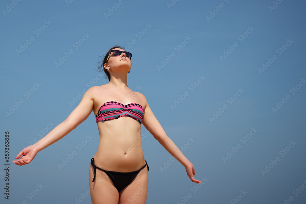 Young woman in bikini takes a sunbath on a clear sky background copyspace Young woman in bikini takes a sunbath on a clear sky background copyspace