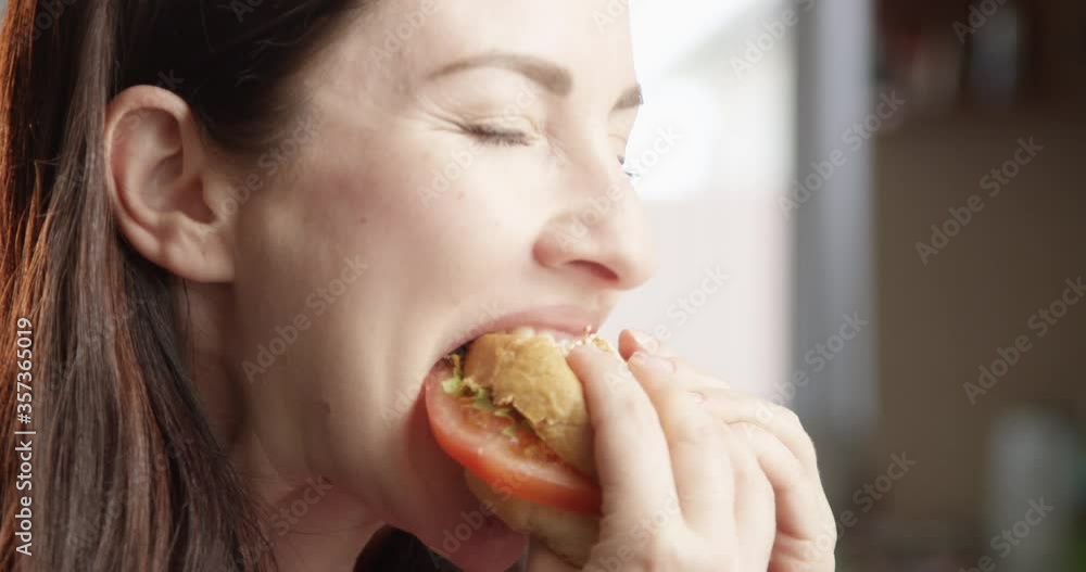Beautiful Woman Eating Cheeseburger with Delight and Indulging with the Taste Indoors with Sun Shining a Close up Shot on Red Camera Beautiful Woman Eating Cheeseburger with Delight and Indulging with the Taste Indoors with Sun Shining a Close up Shot on Red Camera