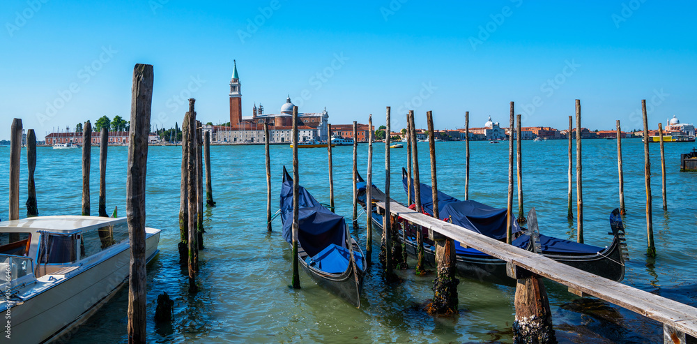 Gondolas moored by Saint Mark square with San Giorgio di Maggiore church in the background in Venice, Italy. Architecture and landmarks of Venice. Gondolas moored by Saint Mark square with San Giorgio di Maggiore church in the background in Venice, Italy. Architecture and landmarks of Venice.