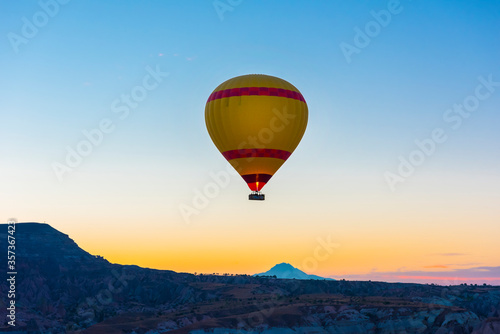 Hot air balloon flying over rock landscape at Cappadocia