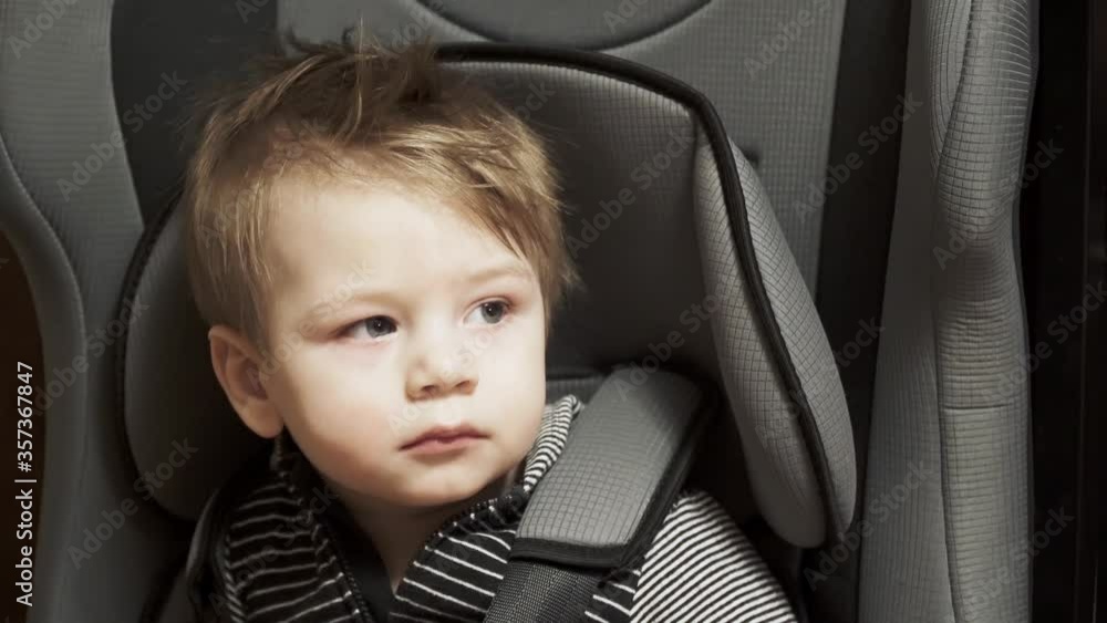 Baby boy sits on a child seat in the car Baby boy sits on a child seat in the car