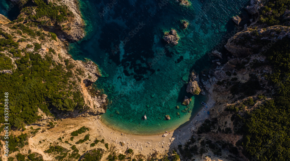 Tranquil drone top down show of an isolated beach with moored boats at Corfu island in Greece