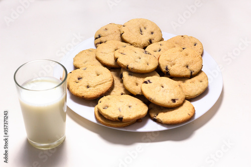Delicious chocolate chip cookies plate with a glass of milk on a white background