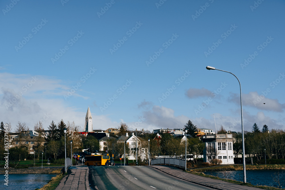 Buildings on the shore of Lake Tjodnin, in Reykjavik, the capital of Iceland. The road over the lake.