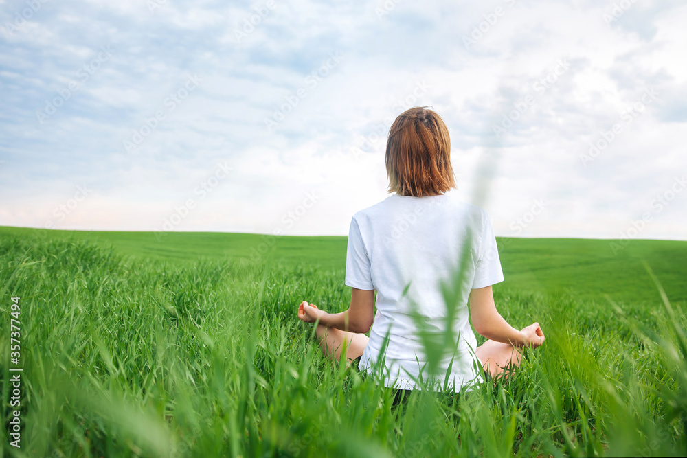 The girl is meditating in nature. Back view The girl is meditating in nature. Back view