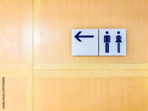Direction sign for toilet with male and female sign on wall wooden