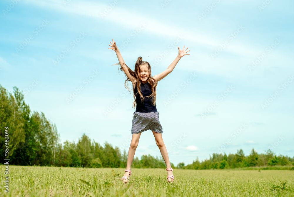 Kid girl jumping on the grass at spring.Summer field, horizon and sky. Happy childhood and freedom.Life Style Outdoors. Kid girl jumping on the grass at spring.Summer field, horizon and sky. Happy childhood and freedom.Life Style Outdoors.