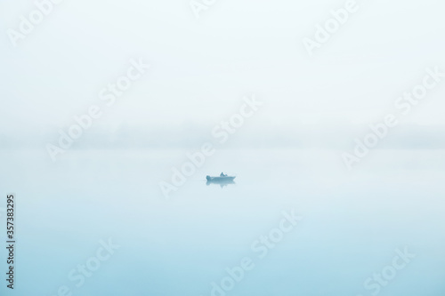 Fotografie, Obraz Lonely fisherman in a boat on  river. Thick fog