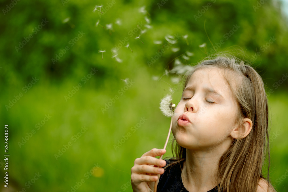 Summer in the park or forest. nature, freshness idea and freedom. happy childhood.Summer joy, little girl blowing dandelion at sunset near the river Summer in the park or forest. nature, freshness idea and freedom. happy childhood.Summer joy, little girl blowing dandelion at sunset near the river