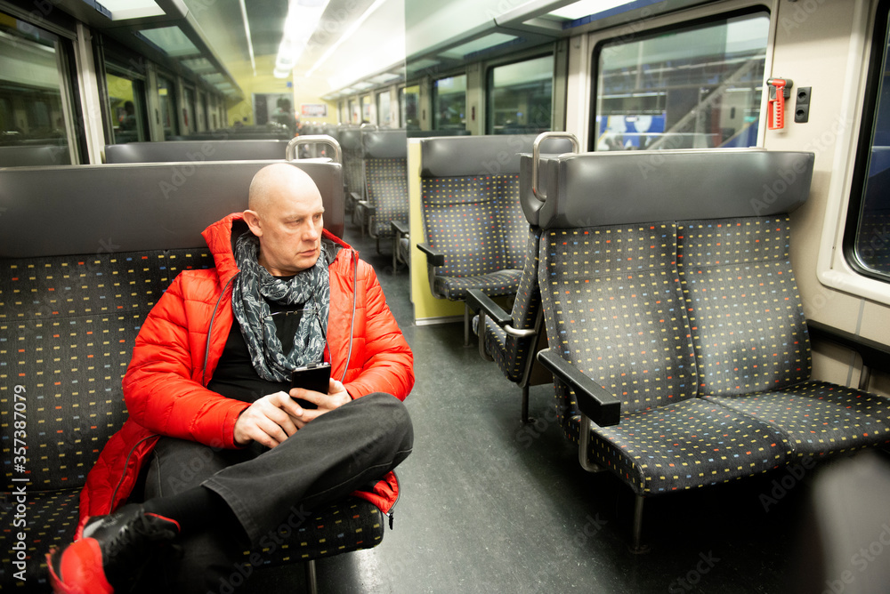 One mature man sits on an empty public transport train and using a cell phone One mature man sits on an empty public transport train and using a cell phone