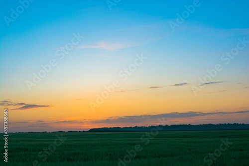 Sunset sunrise over field or meadow. Bright dramatic sky and dark ground.