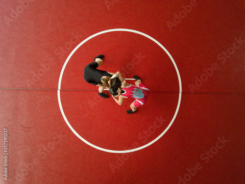 Overhead aerial view of female wrestlers on a red mat