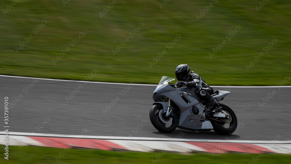 A panning shot of a grey racing bike as it circuits a track