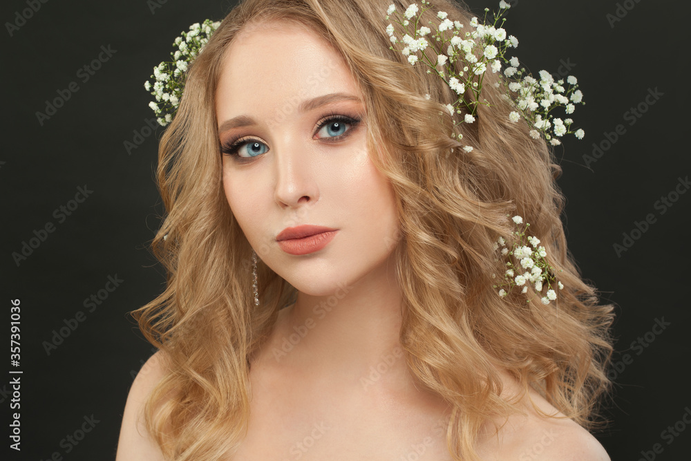Lovely girl with blonde curly hair and flowers, beautiful face closeup Lovely girl with blonde curly hair and flowers, beautiful face closeup