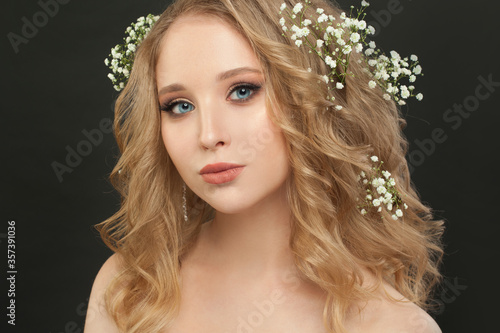Lovely girl with blonde curly hair and flowers  beautiful face closeup