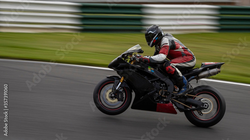 A panning shot of a black racing bike on one wheel as it circuits a track