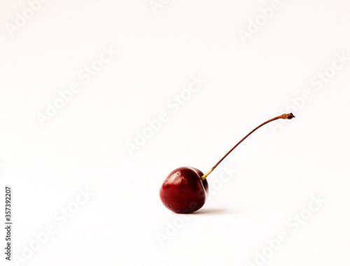 A single ripe cherry on a light background with space for text.