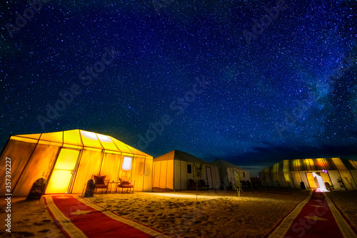 A sky full of staras and milky way above a desert camp in Sahara desert in Morocco.  photo