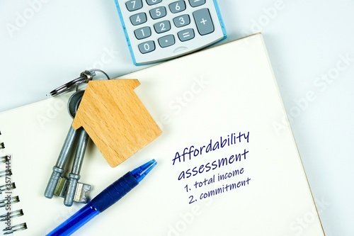 Conceptual image of debt service ratio for home loan repayment appraisal. Wooden key chain calculator notepad and pen in visibility. Focus on keychain.