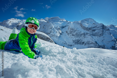 Kid enjoying winter activities in snow over sunny mountain panorama copy space
