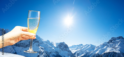 Glass of champagne over the mountain snow range on the good sunny weather