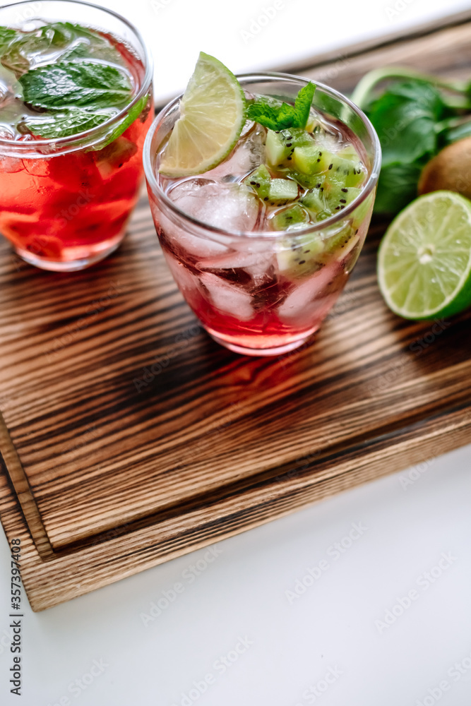Raspberry cocktail, lemonade with lime, kiwi, mint and pieces of ice on a wooden board. Close-up. Raspberry cocktail, lemonade with lime, kiwi, mint and pieces of ice on a wooden board. Close-up.