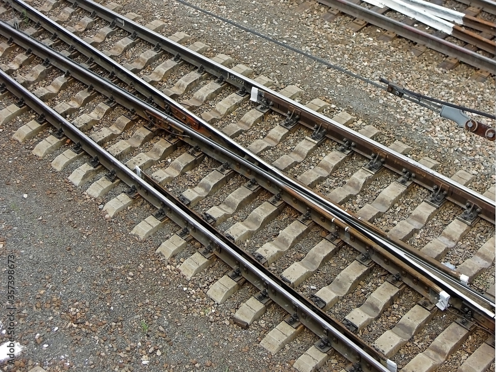 Side view onto railroad tracks. Construction of tracks consist of steel rails, installed on ties (sleepers) & ballast, on which rolling stock, usually fitted with metal wheels, moves Side view onto railroad tracks. Construction of tracks consist of steel rails, installed on ties (sleepers) & ballast, on which rolling stock, usually fitted with metal wheels, moves
