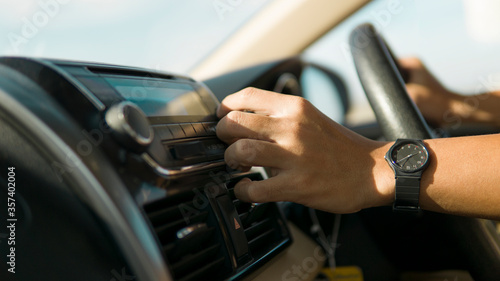 Driver is adjusting radio volume while driving a car under way travel.