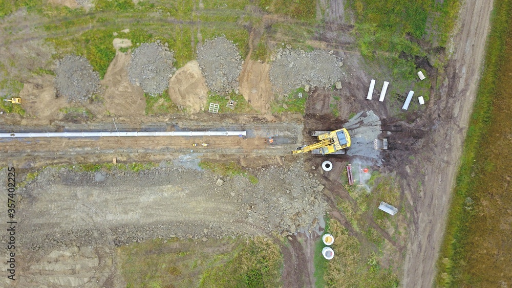 Bagger verlegt eine Leitung aus Rohren in einem Baugebiet, Baustelle ...