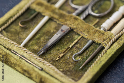 Detail of antique rare sewing kit in open green velvet box with scissor, sewing needles and crochet hooks made of metal and animal bones in very good condition