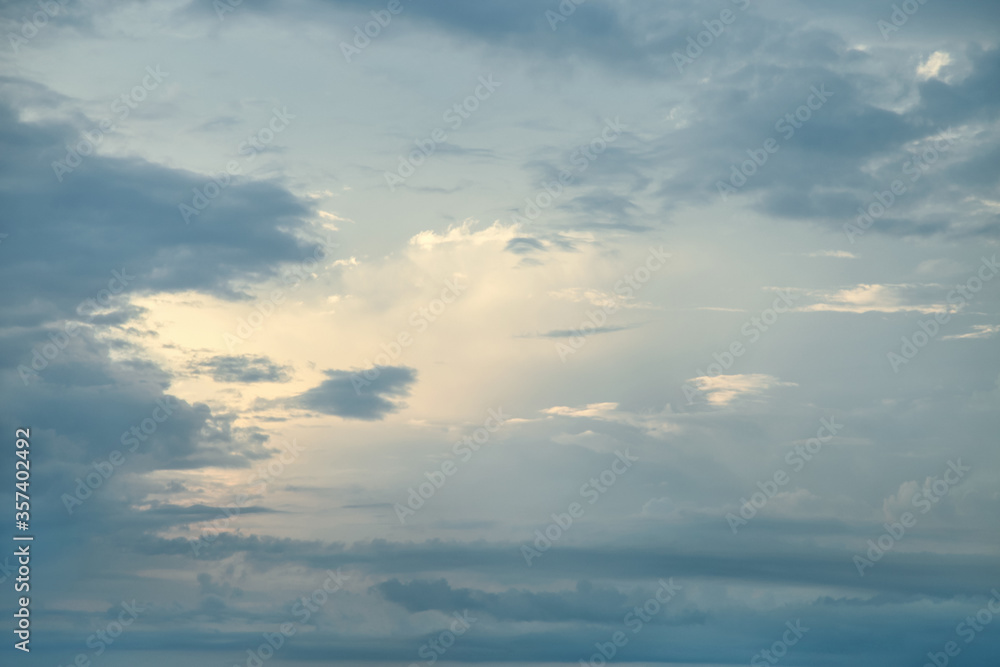 Gray, evening sky with clouds in the rays of the setting sun.