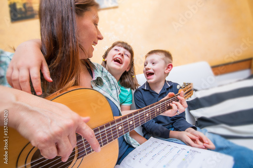 Happy family. Mother and sons playing guitar and sing together. Adult woman playing guitar for children.