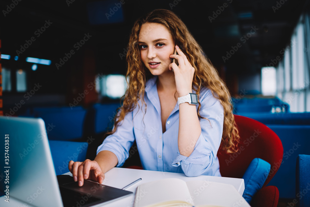 Skilled copywriter having mobile conversation while remotely working in cafe Skilled copywriter having mobile conversation while remotely working in cafe