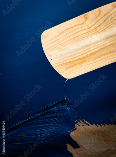 Water dropping from a wooden canoe paddle