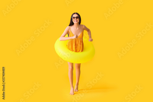 Jumping young woman with inflatable ring on color background