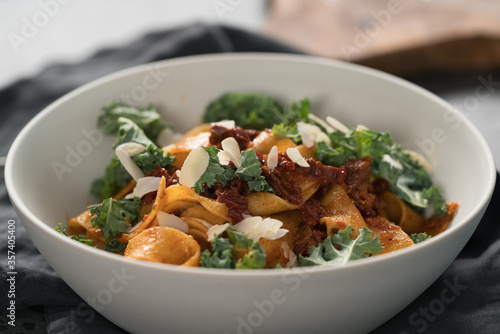 fettuccine pasta with sun-dried tomatoes, almond flakes and kale leaves