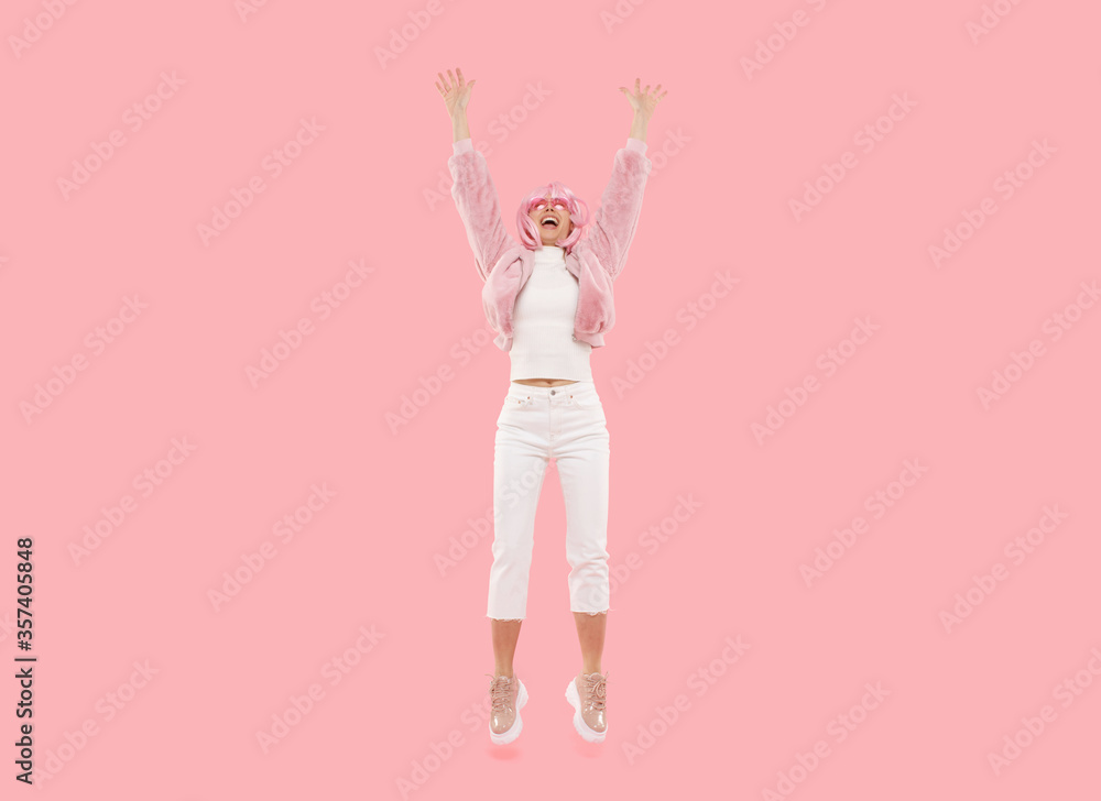 Full length photo of young active female jumping and laughing, isolated on pink background Full length photo of young active female jumping and laughing, isolated on pink background