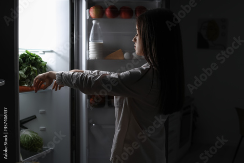 Female sleepwalker near fridge at night photo