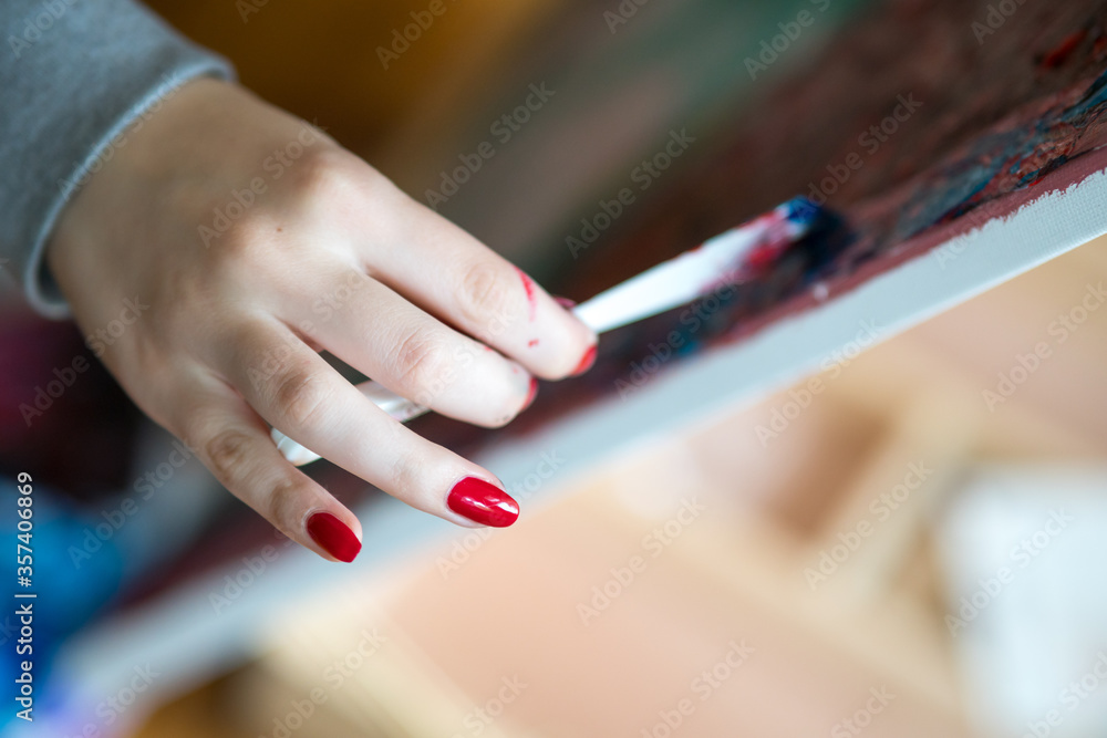 Female artist's hand holding brush and painting Female artist's hand holding brush and painting
