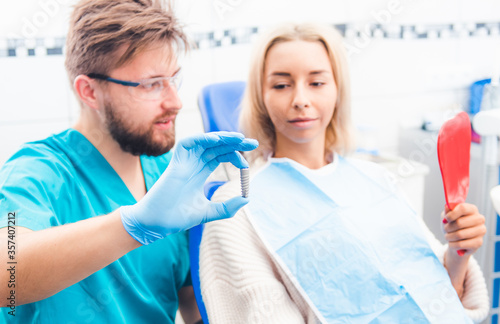 Dentist showing gray implant model to patient