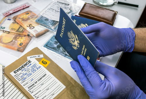 Expert police officer examining American passport of a evidence bag in laboratory of criminology, conceptual image photo