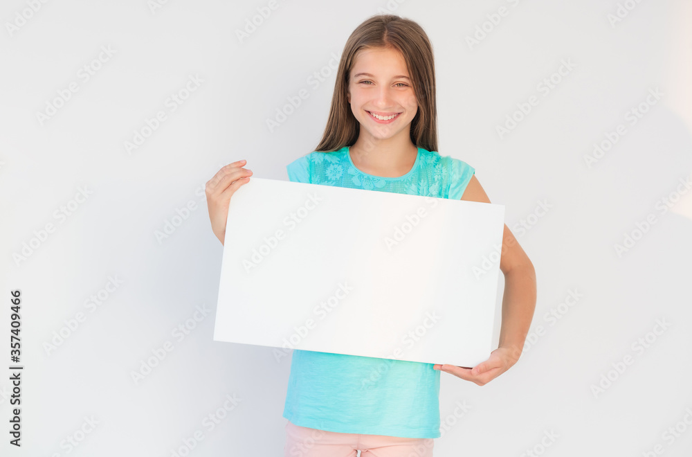 Attractive young teen girl showing blank white canvas banner for advertising Attractive young teen girl showing blank white canvas banner for advertising