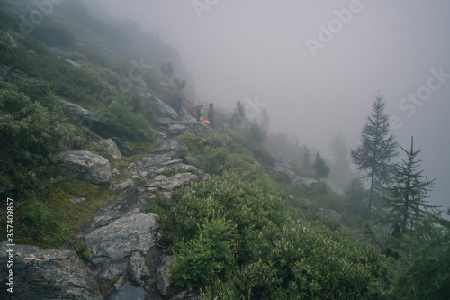 Tourists hiking in foggy Alps